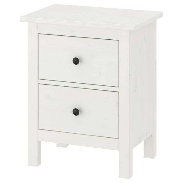 En hvid HEMNES kommode i træ med to skuffer, hver med sorte knopper, der står på fire ben.
