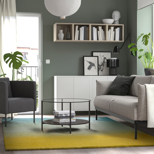 Moderne stue med farverigt tæppe, sofabord, sofa og lænestol.