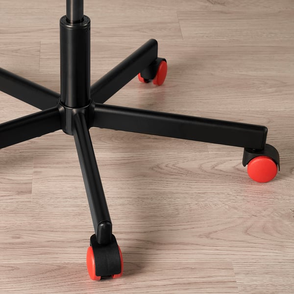 Nærbillede af en detaljeret sort kontorstolsbase med fem røde hjul på lyst trægulv, der viser robust design og kvalitet.
