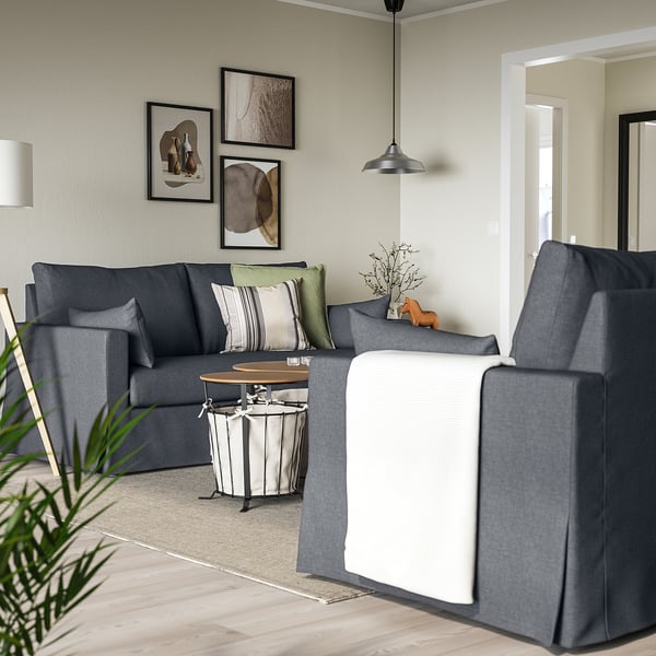 L-formet grå sofa med hynder, puder og sofabord. Moderne værelse med abstrakt kunst og lys.