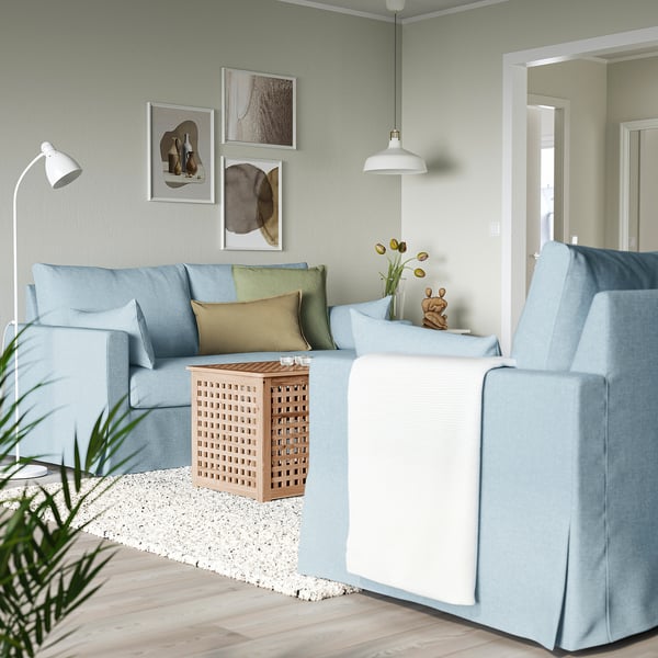 Moderne stue med lyseblå l-formet HYLTARP sofa, sofabord i lyst træ og vægkunst. Sofaen er stor, passer godt til hjørnet.