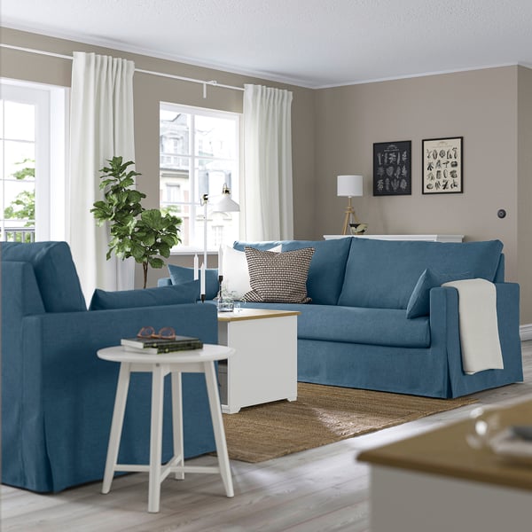 Blå stue med HYLTARP sofa, lænestol, lampe og stort vindue.