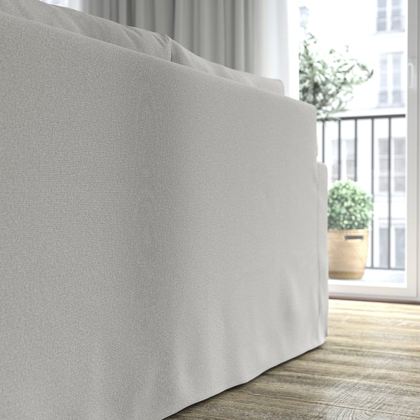 Grå sofa nær stort vindue, indbydende og elegant, med naturligt lys og plante.