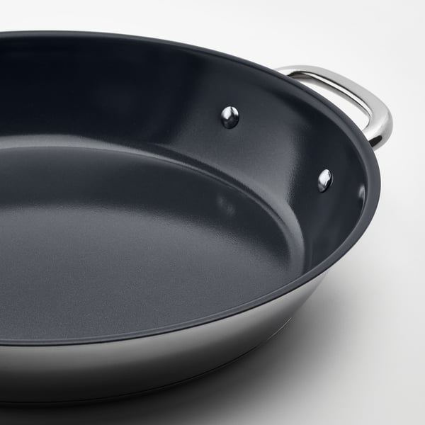 Nærbillede af non-stick stegepande af høj kvalitet med dobbelte håndtag i rustfrit stål, der viser glat, mørk indvendig overflade og robust konstruktion.