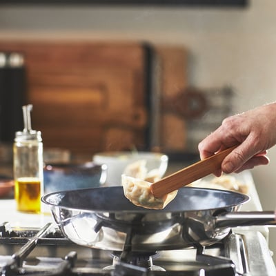 Håndvend dumpling i non-stick pande på gaskomfur.
