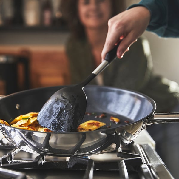 Person, der rører rundt i mad i en non-stick pande på et gaskomfur. Den nemme håndtering og madlavningsfunktion på IKEA 365+ panden.