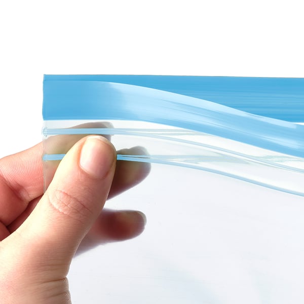 Hånden holder en gennemsigtig, blåkantet, genanvendelig og forseglbar plastikpose, der viser dens kvalitet og design.