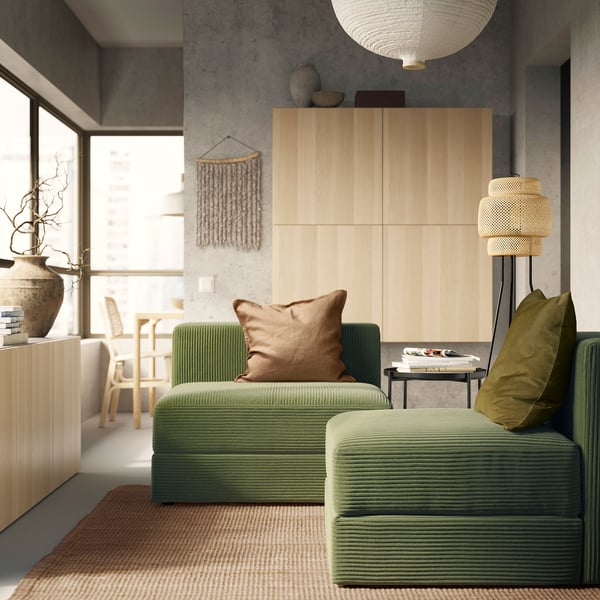 Moderne stue med grøn JÄTTEBO sofa, træskab og vævet lampe.