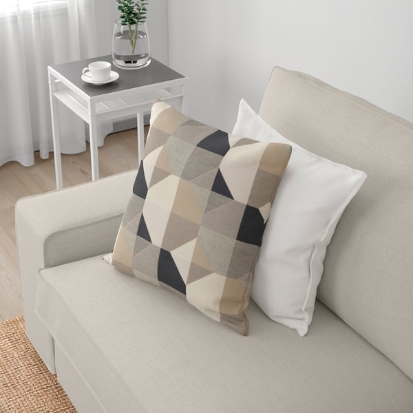 En hyggelig, lys KIVIK sofa med geometriske hynder. Armlænene giver ekstra sidde- eller nakkestøtte.