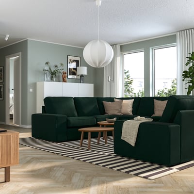 Moderne stue med grøn KIVIK sofa, stribet tæppe, sofabord, pendel, store vinduer, blå vægge, hvidt skab og indretning.