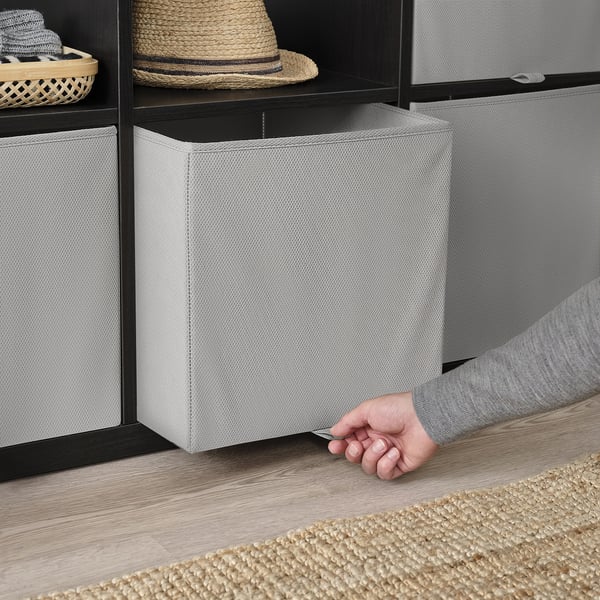 Person, der rækker ind i KOSINGEN opbevaringsboks på hylde. Let at samle og folde, perfekt til at organisere omfangsrige genstande.