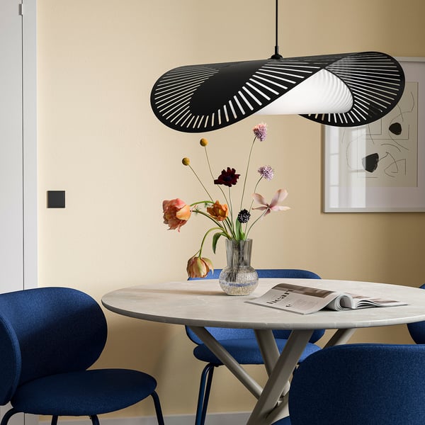 Moderne spisestue med KVÄLLSDOPP sort pendelampe, blå stole, marmorbord og blomstervase, placeret op ad en beige væg med kunst.