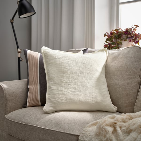 Hyggelig stue med LAGERPOPPEL puder, grå sofa, pyntepude og tæppe. Forstærket med lampe og plante.