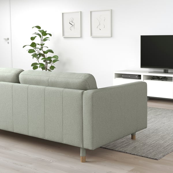 Moderne minimalistisk stue med lysegrøn LANDSKRONA sofa, træben, hvidt tv-bord, sort tv og vægkunst.