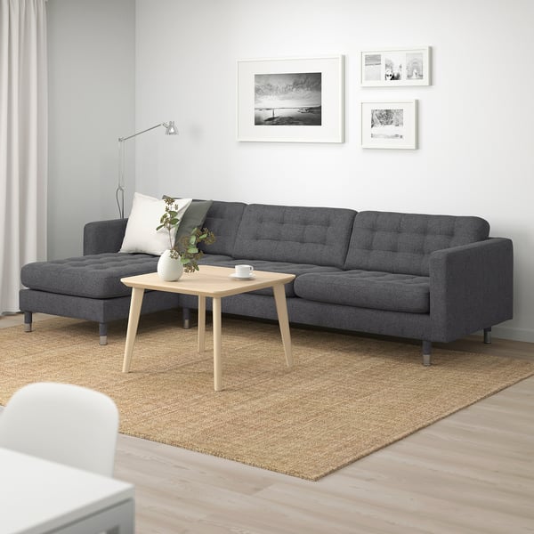 Moderne grå sofa i minimalistisk stue med trægulv og jutetæppe.