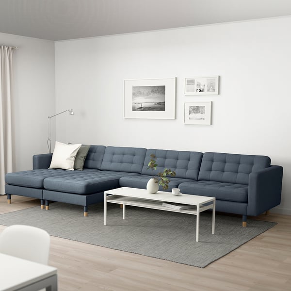 Moderne stue med grå sektionssofa, hvid vægdekoration, sofabord med blomster