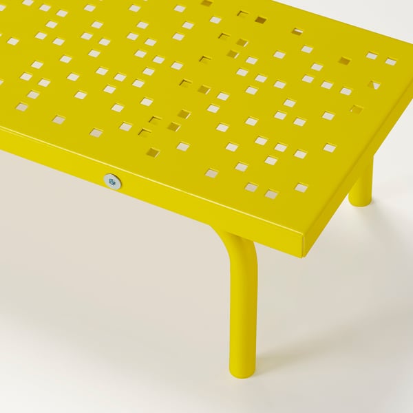 Lysegult metalstativ med perforeret design, støttende ben, sandsynligvis brugt til ergonomisk skærmplacering.