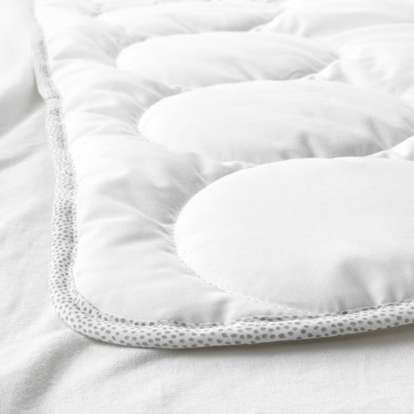 Nærbillede af en hyggelig babydyne af høj kvalitet. Blødt, quiltet stof med en detaljeret, tekstureret kant.