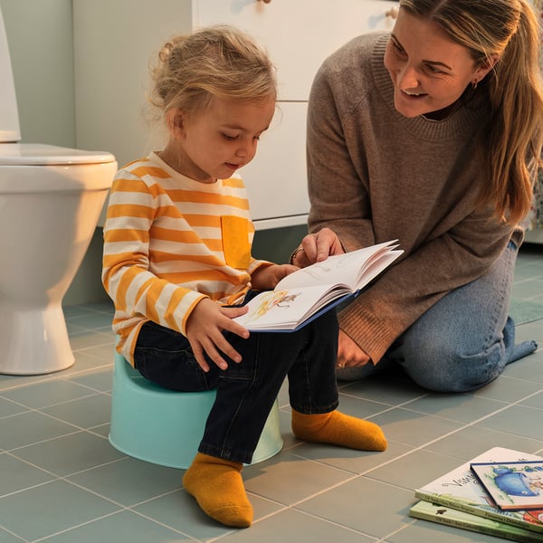 Kvinde og pige læser på grønt toilet.