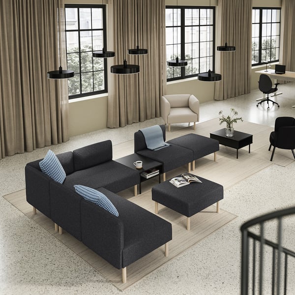 Moderne opholdsstue med store vinduer, med en grå LILLEHEM sofa, sort sofabord, beige lænestol og sort kontorstol.