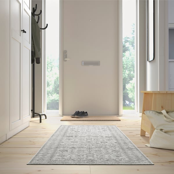 Minimalistisk entré med gråt LOKALTÅG tæppe, bænk, frakke, sko og garderobe.