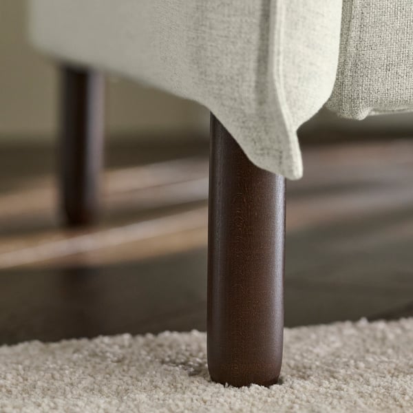 Lys beige sofa med moderne design, høj ryglæn og træben; Fokuser på bløde puder og hyggelig komfort.