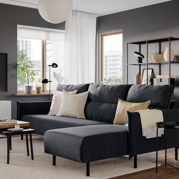Moderne stue med stor grå MANNARP-sofa , puder, tæt ved vinduet med planter.