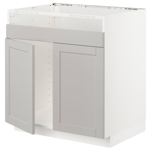 Et hvidt METOD køkkenskab med lysegrå lerhyttan-låger med skrå kanter og et traditionelt design.