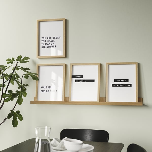 Moderne væghængt hylde viser fire motiverende indrammede prints og en potteplante, der giver både dekoration og inspiration.