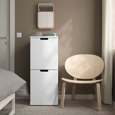Hvid IKEA NORDLI Kommode med 2 skuffer mellem seng og stol, minimalistisk hjørne.