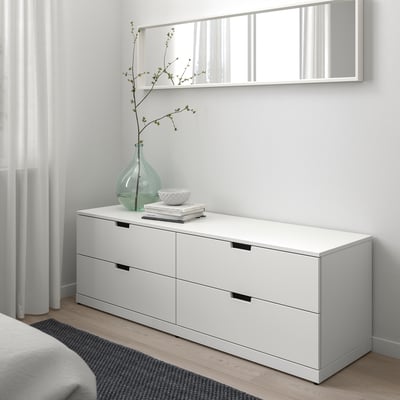 Moderne soveværelse med hvid NORDLI kommode, bredt spejl og grøn vase.