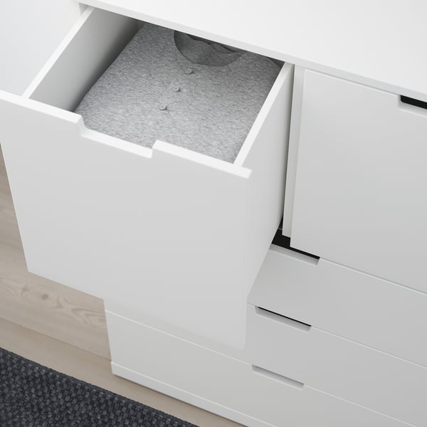 En hvid NORDLI kommode med en åben skuffe, der afslører en grå skjorte, der viser dens opbevaringsfunktion.