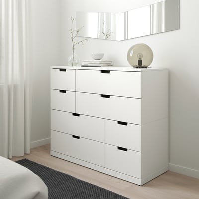 Hvid ikea NORDLI 6-skuffers kommode i soveværelset, moderne og minimalistisk, tæt på vindue, med lampe, vase og bøger.