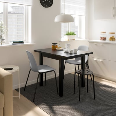 Moderne spiseplads med NYMÅNE lys, grå stole, hvide skabe og naturligt lys.