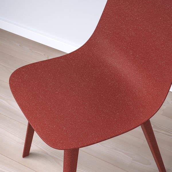 Nærbillede af rød, tekstureret stoleryg, en del af ODGER. Viser træ-plast komposit, slankt design.