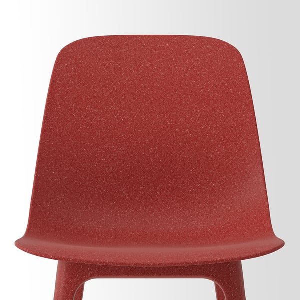 Rød stol med plettet tekstur, glatte kurver, behageligt design.
