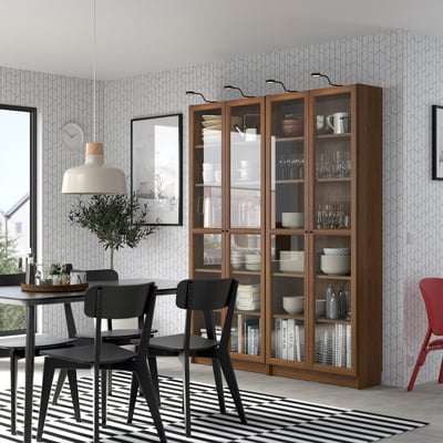 Moderne spisestue med OXBERG reol, hvide fade, sorte stole, stribet tæppe og stor pendel.