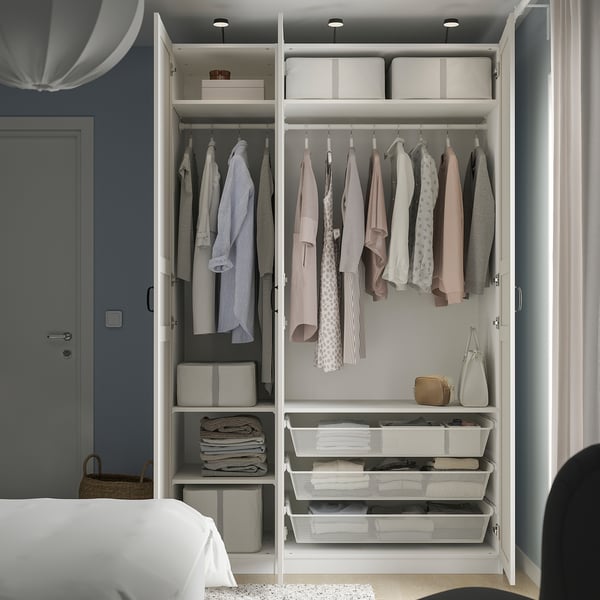 Organiseret garderobe med tøj, kasser og skuffer; spejldøre udvider pladsen.