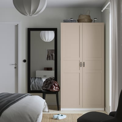 Moderne soveværelse med PAX garderobeskab, spejl, bord. Hjørnegarderobe, gråt sengetøj, blødt lys, minimalistisk design.