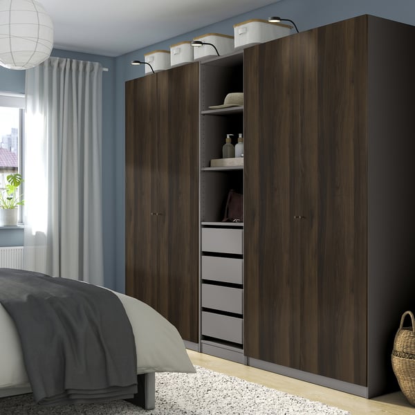 Moderne soveværelse med stor mørk PAX garderobe i træ, høj, multi-rum, integreret belysning, hyggeligt, organiseret.