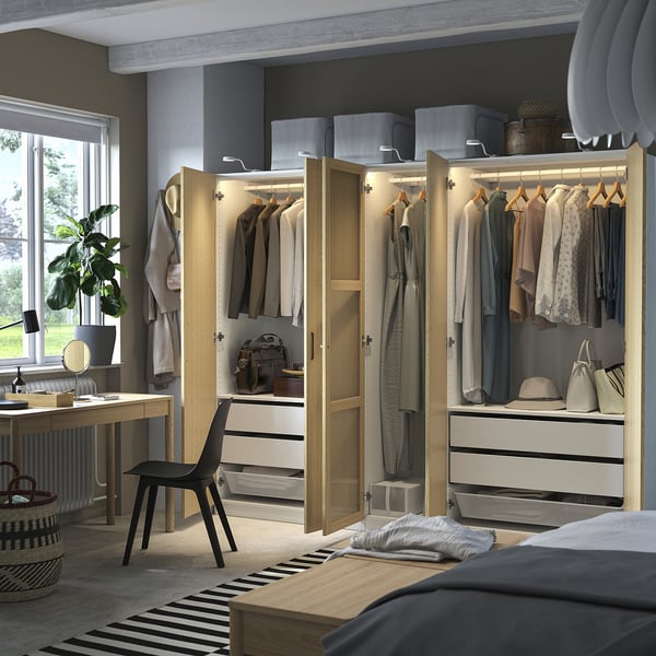 Et velorganiseret soveværelse med PAX-garderobe med tøj, tilbehør og en sort stol.