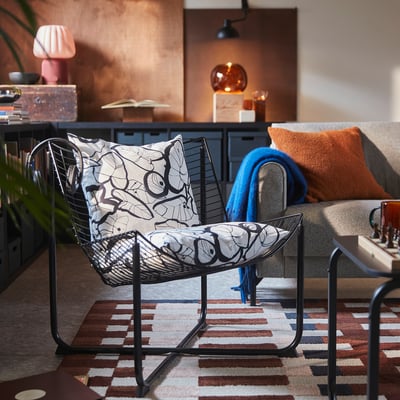 PELARKÖRSBÄR sort og hvid bladpude på stol, orange pude på sofaen, trendy tæppe.