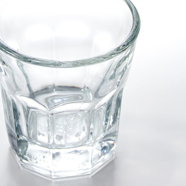 En klar, uberørt glaskop sidder på en hvid overflade med en diamantskåret tekstur omkring kroppen for et klassisk, elegant look.
