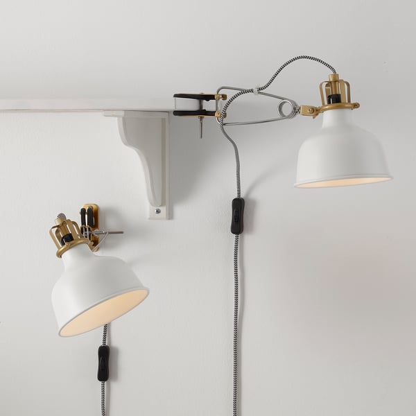 To hvide RANARP lamper på en væg, den ene justeret, begge med stofsnore og justerbare led.