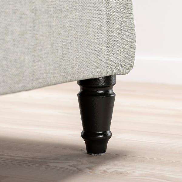 Nærbillede af sengeben dækket af gråt stof med sort finish.