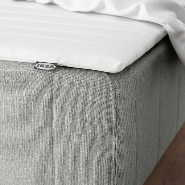 Seng med hvid IKEA RENFJÄLLET madras på grå bund.