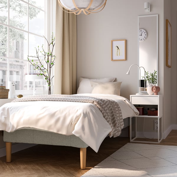Soveværelse med RENFJÄLLET-seng, træsengegærde, beige/hvidt sengetøj, lampe, stort vindue, indretning. Rummeligt.