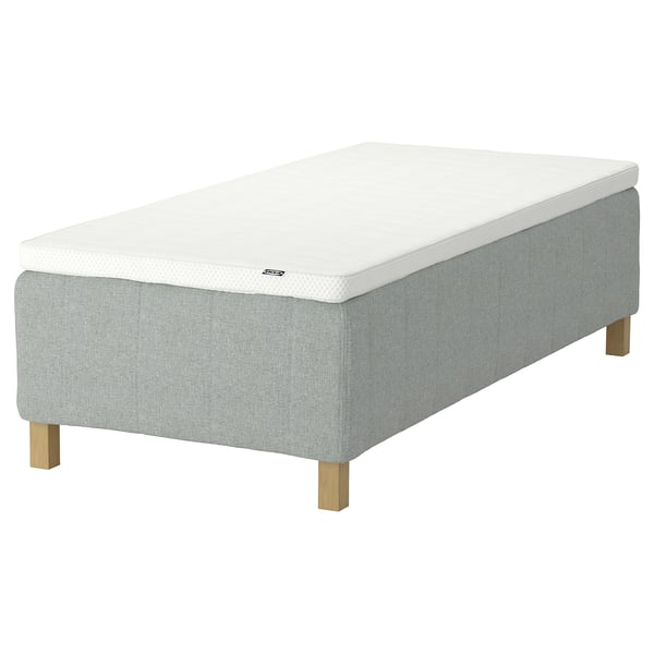 En IKEA RISHÖJDEN hvid og grå seng. Sengen har en rektangulær form med stofbetræk og træben.