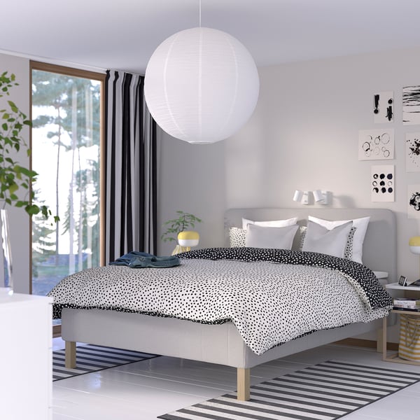 Moderne gråt soveværelse med RISHÖJDEN seng, hvid lampe, stort vindue, stribet tæppe og kunst.