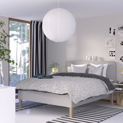Moderne gråt soveværelse med RISHÖJDEN seng, hvid lampe, stort vindue, stribet tæppe og kunst.